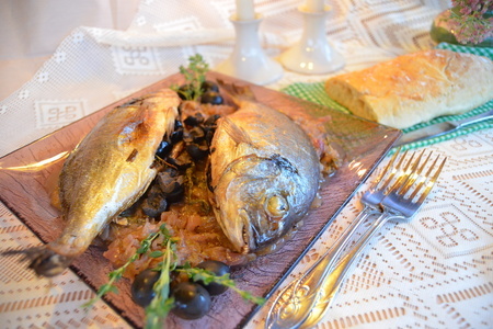 Фото к рецепту: Дорадо, запеченная с вялеными томатами, маслинами и тимьяном на луковой подушке