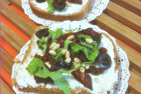 Фото к рецепту: Бутерброд со сливочным сыром, вялеными помидорами, маслинами и кедровыми орешками